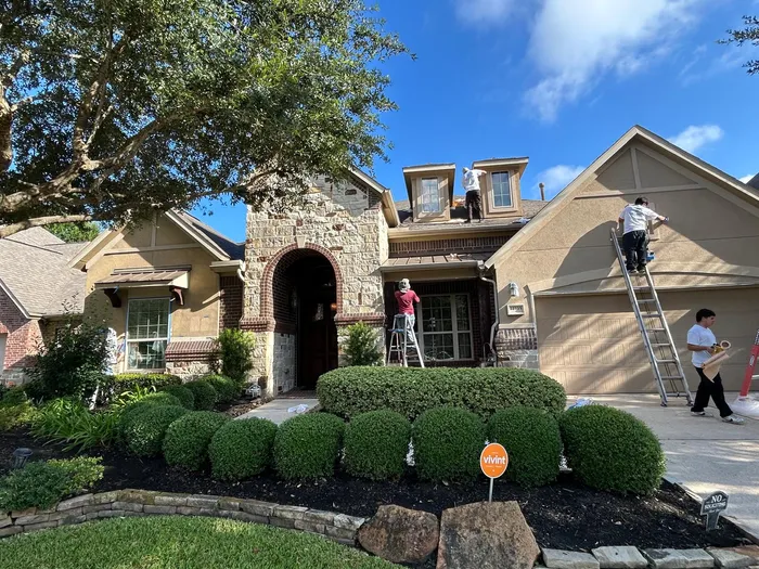 AA Home Remodeling crew painting a stone and stucco home exterior in Houston